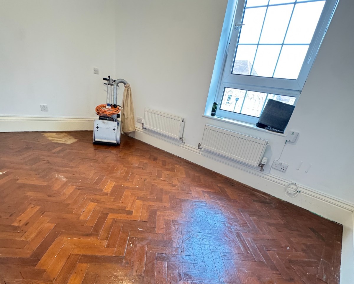 Wood Floor Sanding set up on a dark oak herringbone parquet floor in a bright room, ready for refurbishment.