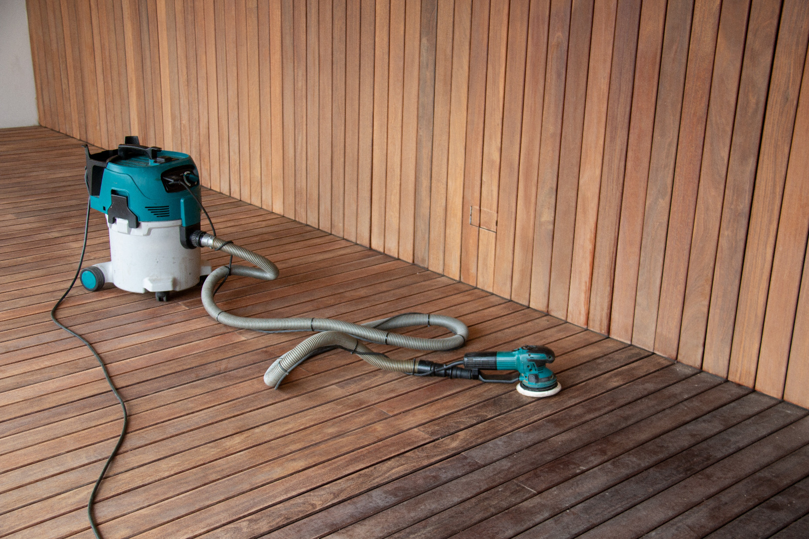 Deck Sanding in City – dust-free sanding equipment on a hardwood timber deck floor, preparing the outdoor decking boards for refinishing.