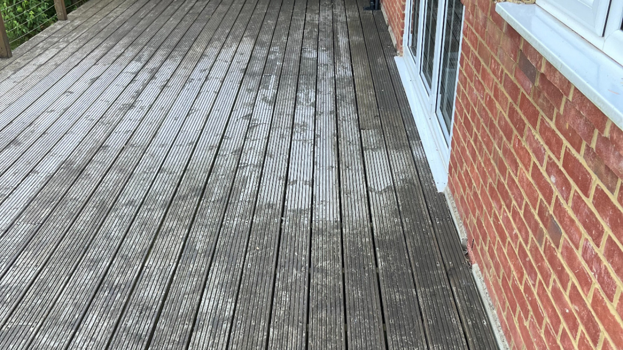 Deck Sanding in City – weathered grooved softwood garden deck floor beside a brick house, showing grey, slippery boards before restoration.