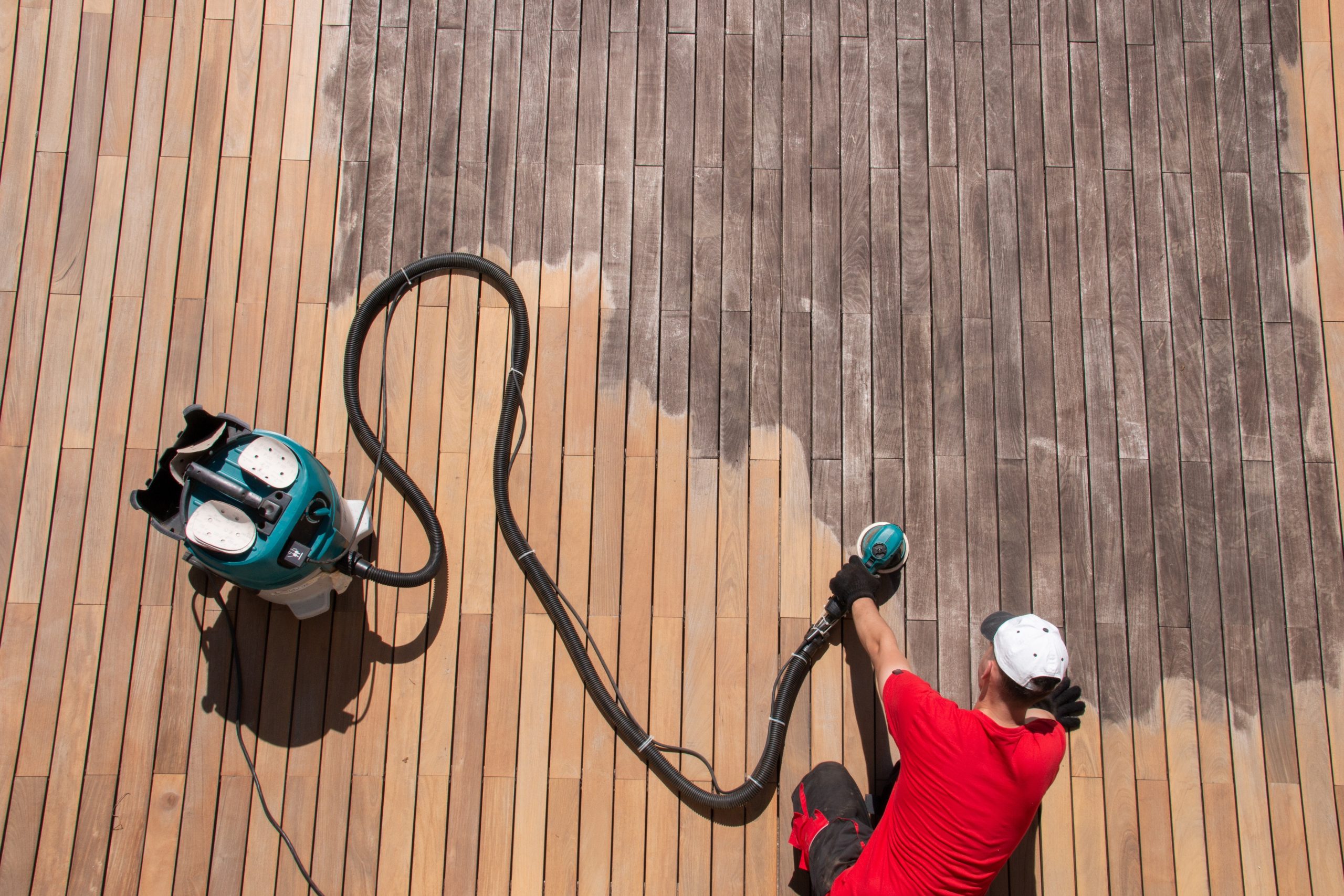 Deck Sanding in City – professional sanding in progress on a large hardwood garden deck floor, revealing fresh timber beneath the grey, weathered surface.