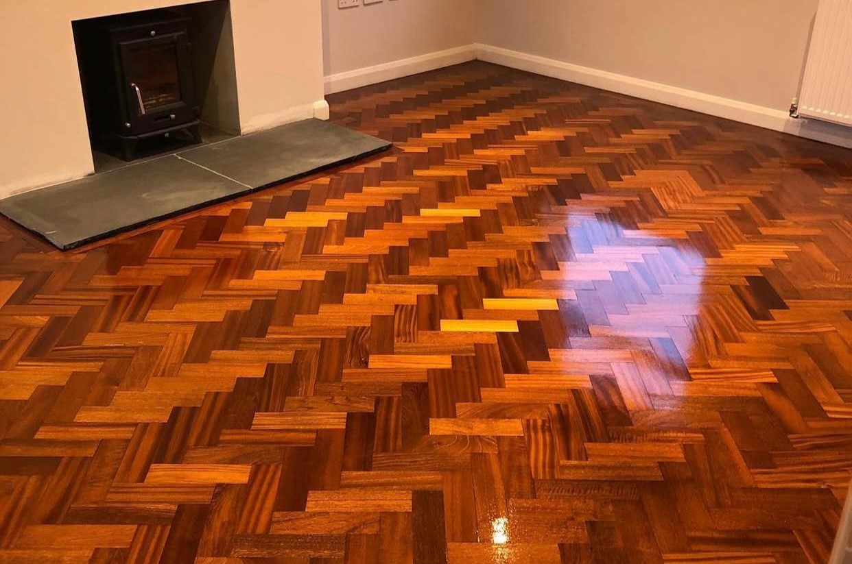 Parquet Floor Restoration on a dark oak herringbone parquet wood floor with a rich high-gloss finish, highlighting the restored pattern, colour and natural grain.